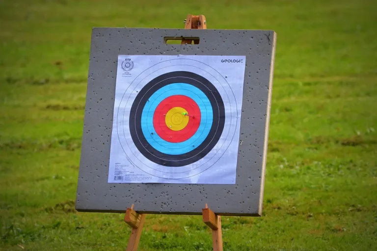 Archery release with an arrow flying downrange and the archer in follow-through at an outdoor range