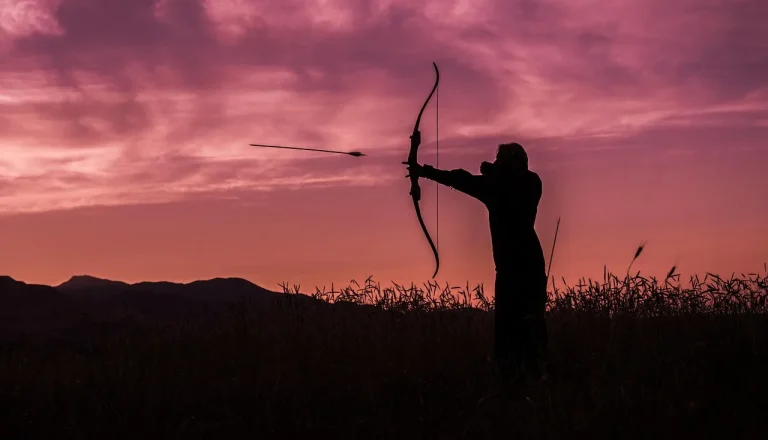 Beginner archer adjusting a leather archery shooting glove while holding a recurve bow at an outdoor range