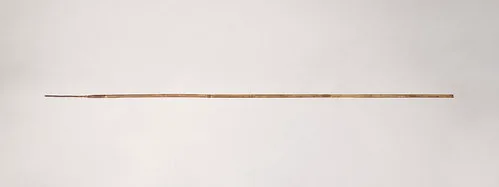 Hands flex-testing a wooden arrow shaft on a spine gauge in a workshop