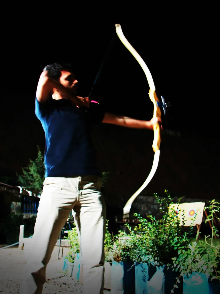 Close-up of hands comparing a compound bow sight and a recurve bow grip