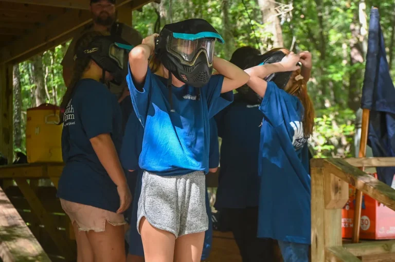 Youth archer comparing an archery glove and shooting tab with a coach at an outdoor range