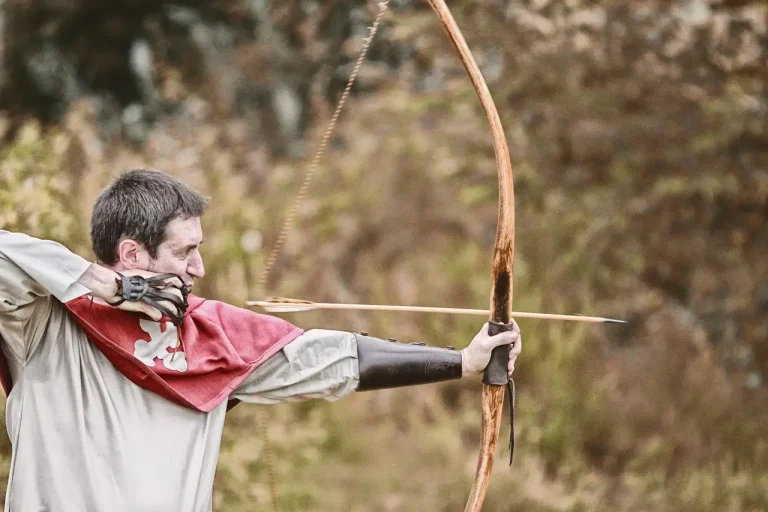An archer compares a hand-built arrow setup with a store-bought set on a workshop bench.