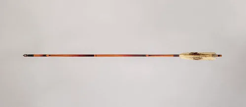 Hands checking a bamboo arrow shaft with calipers on a workbench