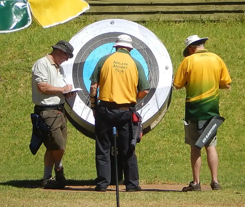 Archery tournament official reviewing scorecards at an outdoor scoring table
