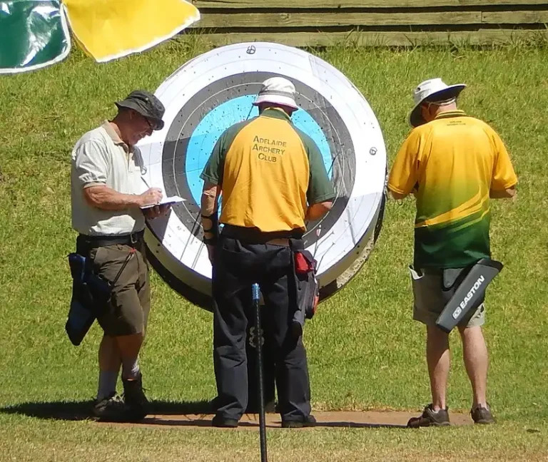 Archery tournament scorekeeping station with clipboard, tablet, and officials outdoors