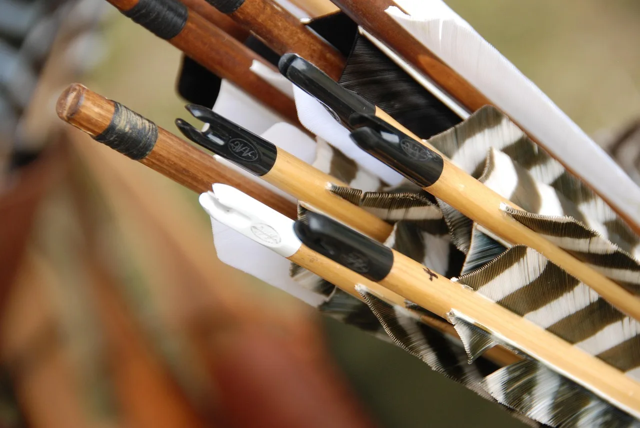 Hunter adjusting arrow rest and broadhead arrows at an outdoor range