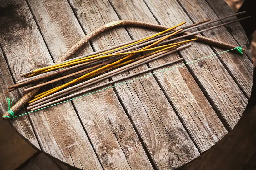 Hands measuring an arrow shaft with calipers beside vanes and target points