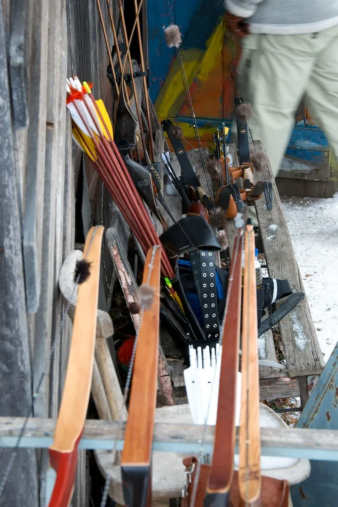 Gloved hands adjusting a release aid and arrow rest on a compound bow