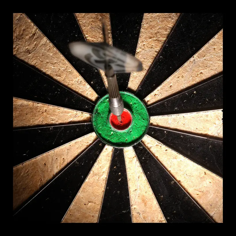 Hands adjusting a target bow sight, stabilizer, and arrow rest at a range table