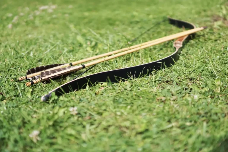 Archer comparing an Easton arrow spine chart with carbon arrows on an outdoor range bench