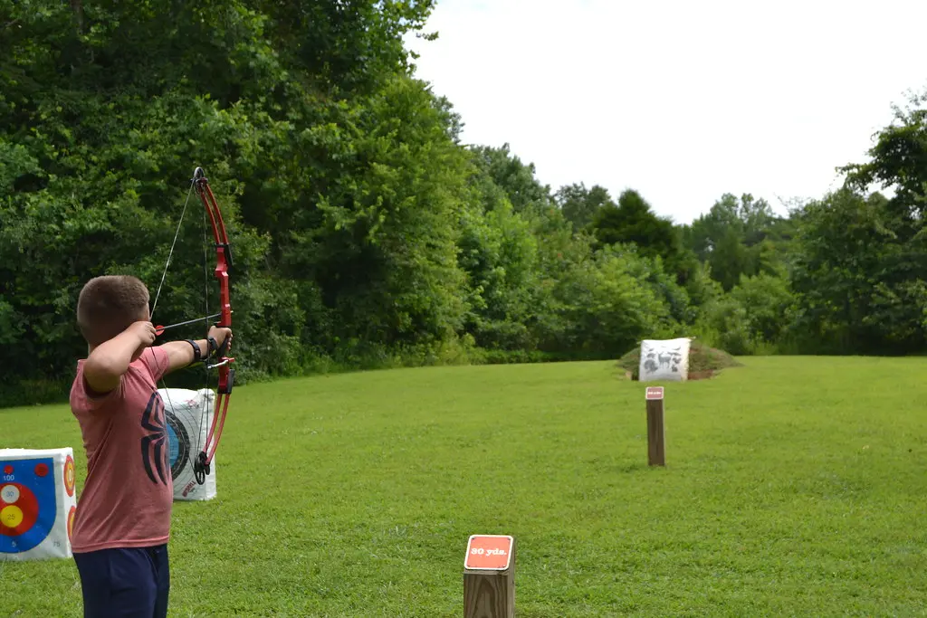 Close-up of a beginner recurve bow and starter archery accessories on a bench