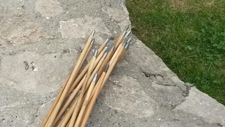 Native American craftsperson straightening a wooden arrow shaft by hand near a small heat source