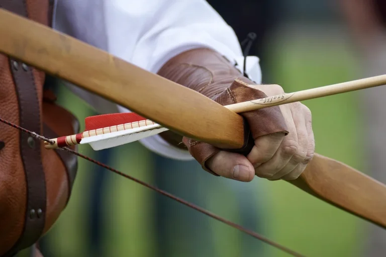 DIY archer choosing a wooden stave for a traditional bow in a home workshop