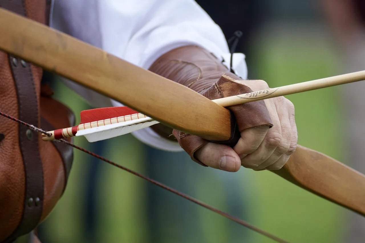 DIY archer choosing a wooden stave for a traditional bow in a home workshop