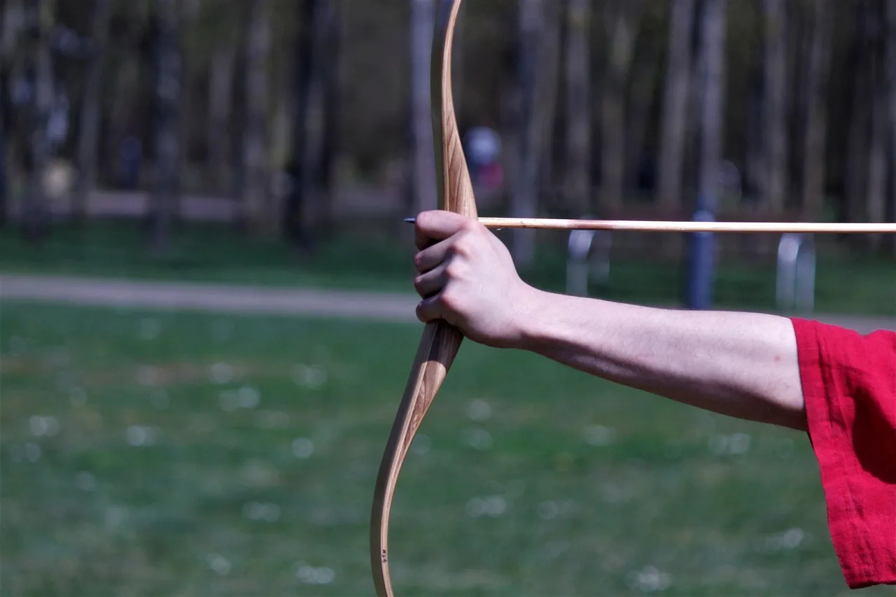New archer comparing an index release and a thumb release with an instructor at an outdoor range