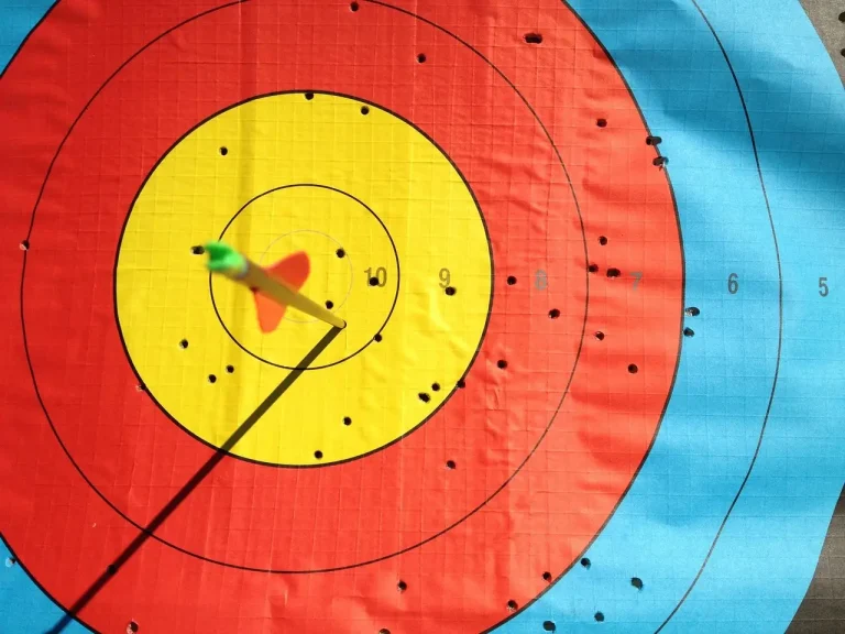 Recurve and compound archers competing indoors with target lanes and officials in a sports hall