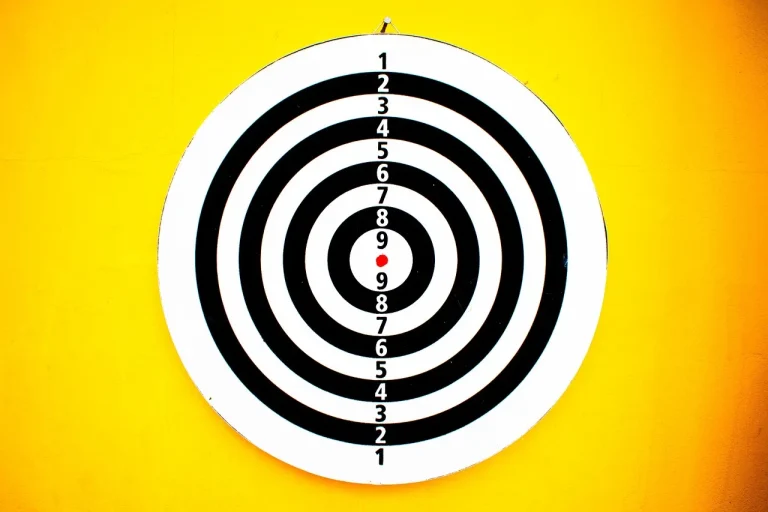 Morrell Yellow Jacket target beside a compound bow with field-tip arrows outdoors