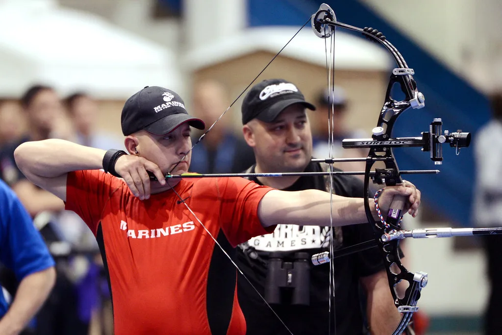 Close-up of a compound bow cam and gloved hand during the draw cycle