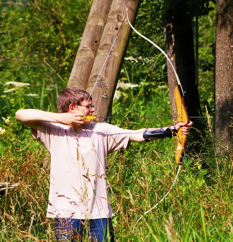 Primitive arrow shafts with sinew wrap, pitch glue, and feather fletching on a workbench