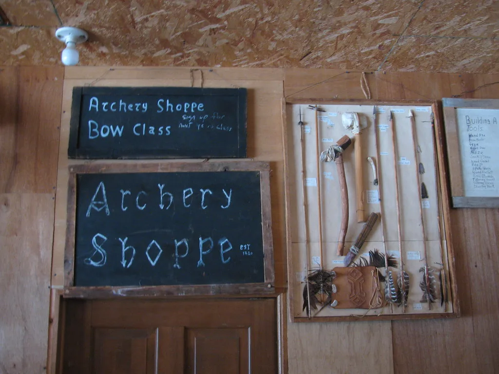 Hand checking a bamboo arrow shaft for straightness on a workshop bench
